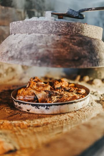 Peka under the bell Peka cooking Dubrovnik iron bell lifted over embers traditional Croatian dish